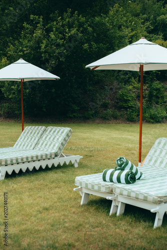 Cuadro en lienzo Elegant green checkered sun loungers with white parasols and rolled towels on ma