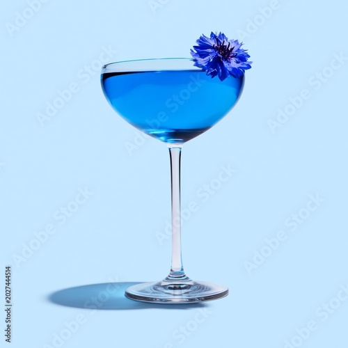 Bright Blue Drink in a Clear Glass With a Flower on a Light Blue Background