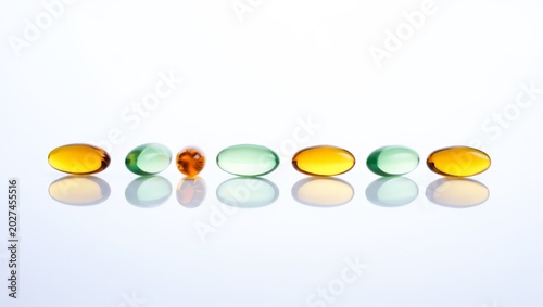 Foto Studio close-up of seven softgel capsules in alternating amber and pale mint gre