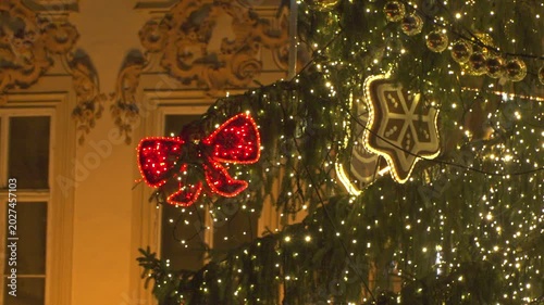Decorated christmas tree with glowing lights and ornaments in Prague. bright fairy lights and red bows. Large gingerbread hearts and golden baubles decorate the green branches