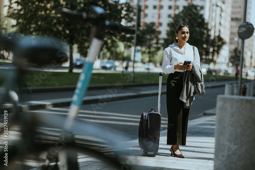 Woman stands near suitcase ...