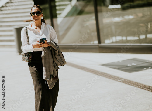 Woman walks with phone in h...