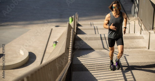 Foto Man runs on stairs in modern urban area during sunny day