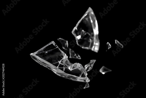 Shattered glass shards flying through the air on a black background, sharp transparent broken glass fragments in motion