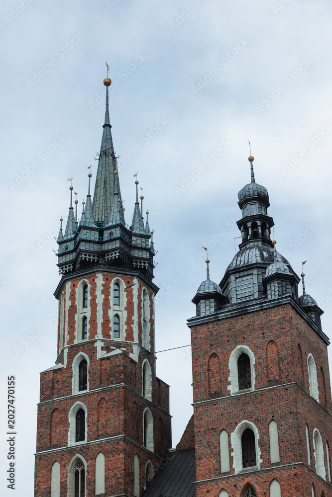 Fototapeta premium Church towers stand tall against the sky in Krakow during an overcast day