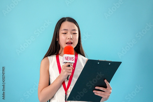 Young asian woman journalist reporter holding microphone and clipboard