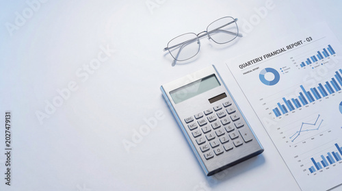 silver calculator, glasses and quarterly financial report with graphs on light desk. business accounting, audit and economic analysis concept. corporate statistics. banner, website header, copyspace.