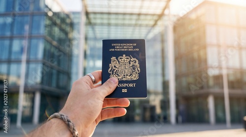 hand holding united kingdom passport against blurred modern glass office building. british citizenship, international travel, business trip, immigration concept. website header, banner with copyspace.