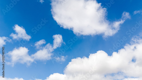 Bright blue summer sky texture filled with white scenic clouds