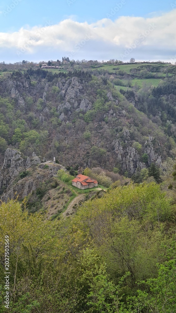 Fototapeta premium La magnifique chapelle auvergnate Notre-Dame d'Estours vue depuis les hauteurs avec les gorges de la Seuge juste derrière (Haute-Loire, Auvergne, France)