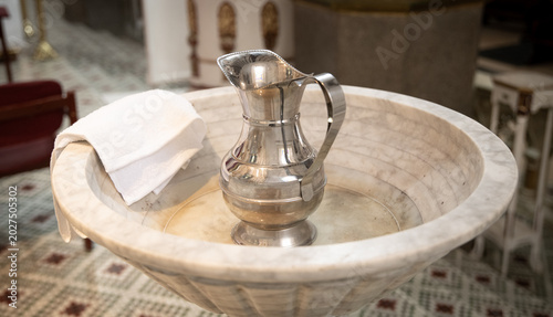 Tableau sur toile Silver ewer beside Catholic baptismal font