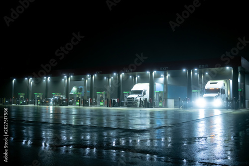 Industrial heavy trucks parked at service station refueling point night