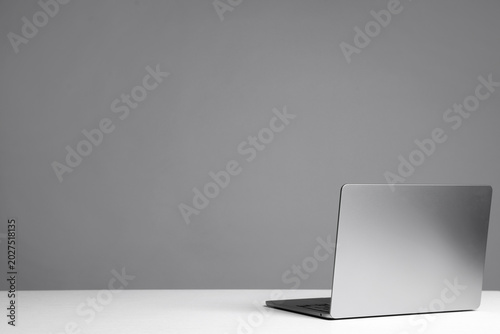 Stylish workplace. Modern laptop on white table against gray background. Space for text