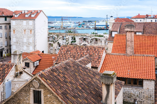 Obraz na plátne Aerial Split: Red roofs, ancient stone, busy port with ferries on the calm Adria
