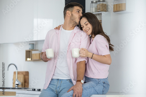 Bilde på lerret Young couple sharing coffee and affectionate moment in modern kitchen on cozy mo