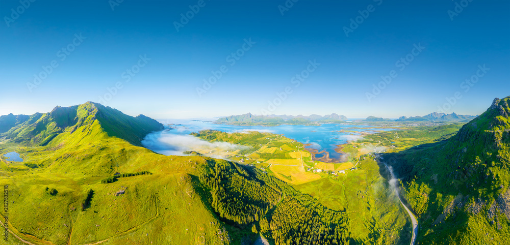 Fototapeta premium Drone view of a fjord in Leknes, Lofoten Islands, Norway. Panoramic aerial view of the northern summer. Scenic arctic landscape with high hills, ocean and northern nature. Background and wallpaper.