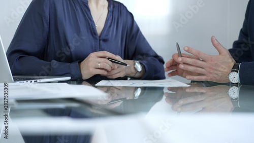 Business people or lawyers reviewing and discussing contract during a meeting, using a laptop and documents on a glass table. Businesspeople concept