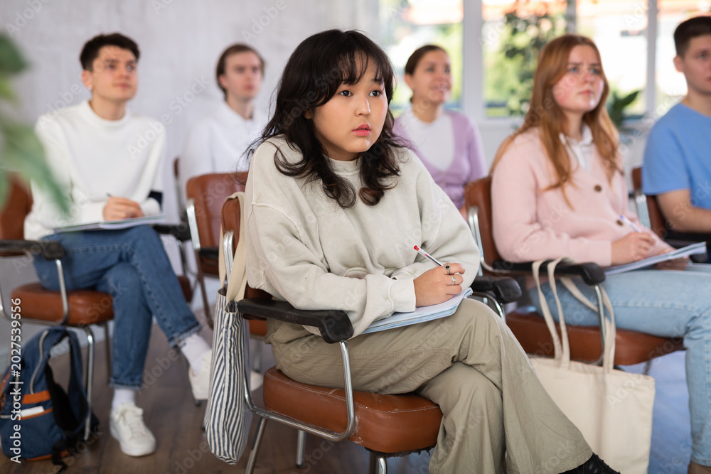 Fototapeta premium High school students sit at their desks and listen carefully to the teacher at the lesson at school