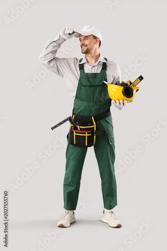 Male technician with tools on light background
