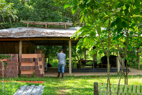 Foto Local Guide Standing Near Rustic Structure in Lush Greenery.