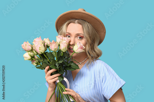 Young woman with bouquet of beautiful roses on blue background