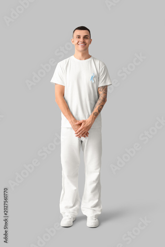 Handsome man with blue ribbon on grey background. Prostate cancer concept