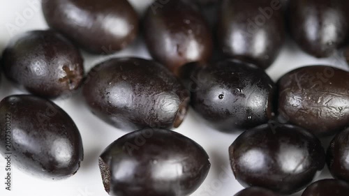 Closeup of moist black olives on white background. Highresolution closeup capturing glossy black olives with rich textures and subtle highlights for visual appeal