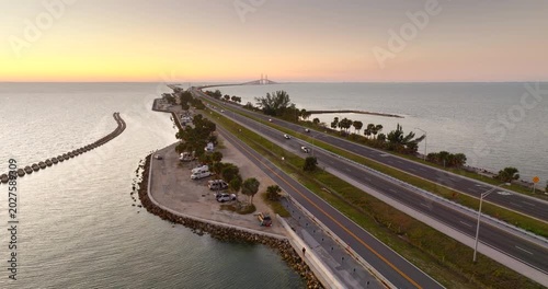Motorhome scenic parking at Florida coastline with view of bridge and sunset sky. RV waterfront recreational area.
