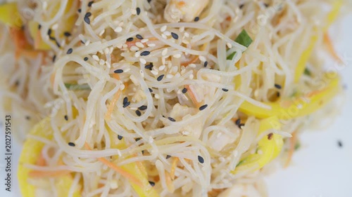 Vermicelli noodle dish. Fresh noodle salad with herbs. Light rice noodles with vegetables and seeds. Closeup of flavorful vermicelli salad garnished with sesame and herbs