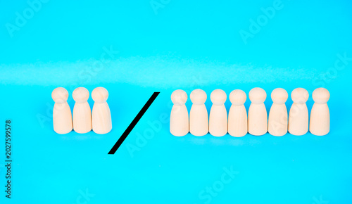 Bilde på lerret Two groups of wooden people figures divided by a slash, representing comparison, majority and minority contrast, demographics, and organizational analysis
