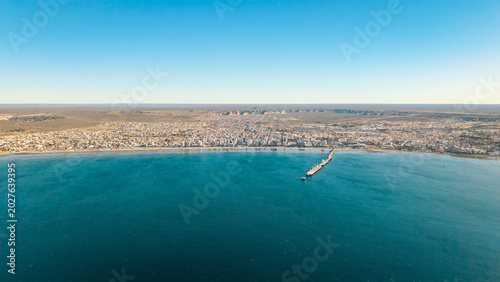 Panoramic aerial view of Puerto Madryn bay and Patagonian coastline under clear blue sky.