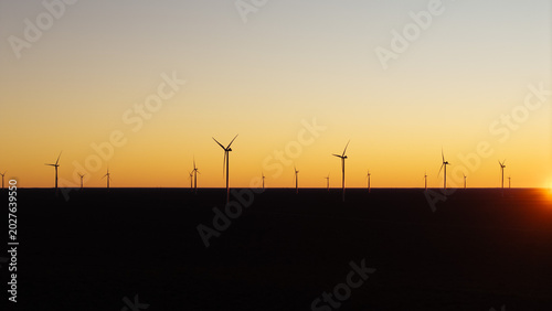 Minimal wind turbine silhouettes at sunset representing renewable energy and sustainable future.