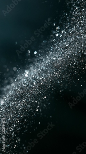Dark background with sparkling silver particles floating diagonally