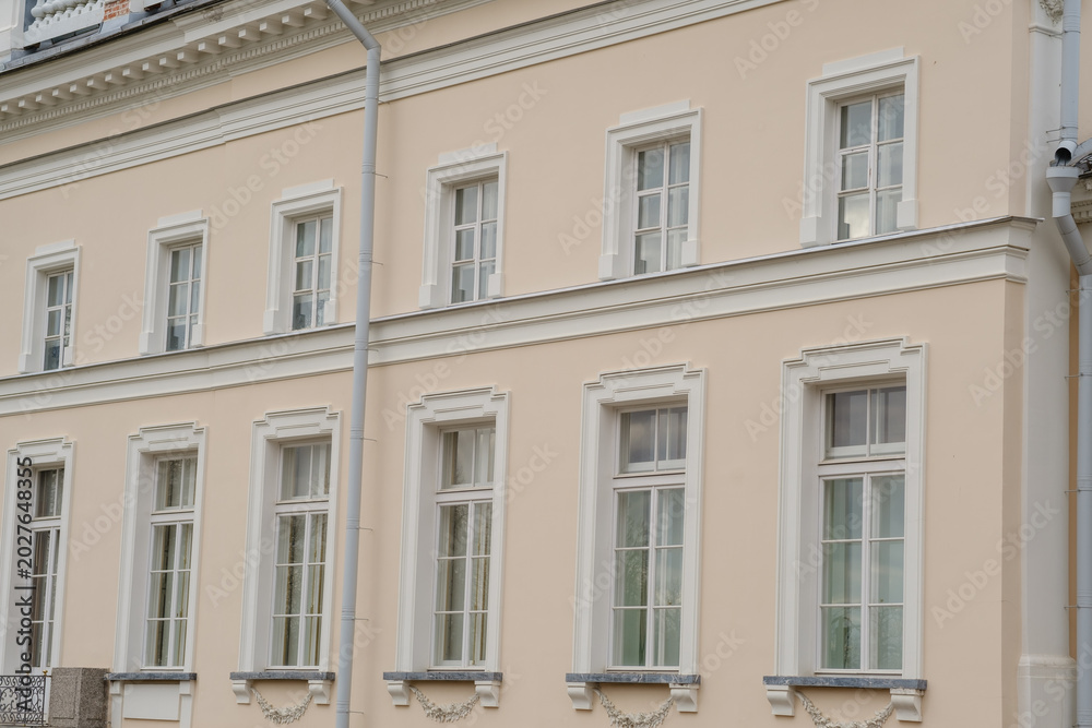 Obraz premium Historic building facade featuring several windows with decorative trim and a light pastel color scheme, showcasing classic architectural elements