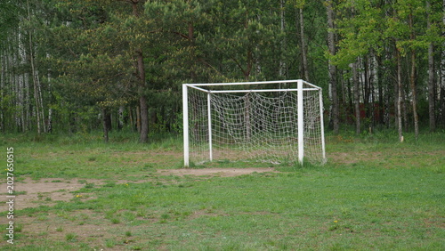 Fotografie White soccer goal standing on an overgrown green grass field with a dirt penalty