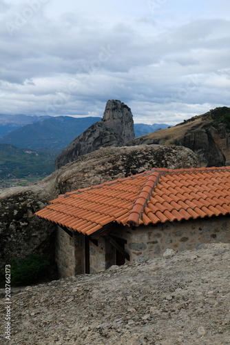 red tiled roof against the backdrop of rocks in cloudy weather