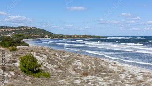 Fotografija Sandy dunes along Sardinia's coastline with waves crashing on the shore