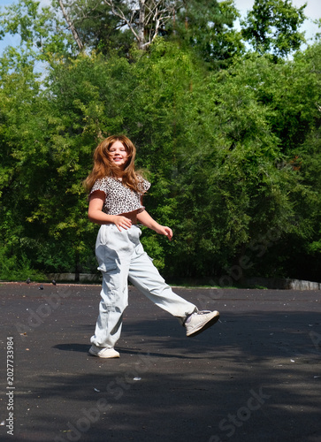 Happy young girl enjoys walking, dancing and jumping freely in the summer sun. Blurred motion captures the energy of the moment, celebrating freedom, carefreeness and individuality.
