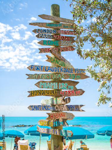 Fotografie Close-up of a wooden directional sign with painted global city names and mileages on Key West beach
