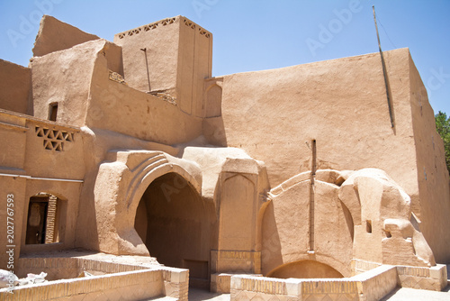 Traditional mud-brick building in the old town of Yazd, Iran, with clay walls, an arched doorway and a windcatcher tower, illustrating the distinctive desert architecture of central Iran.