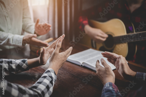 Bild auf Leinwand Group of christian sitting praying and worship God by playing guitar and sing a song together in home, musical devotion gathering, instrumental praise moment, christian worship meeting concept