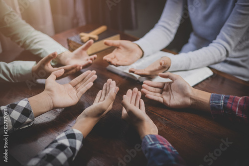 Bilde på lerret Group of Christian  holding hands praying worship together to believe and Bible on a wooden table for devotional for prayer meeting concept, teamwork