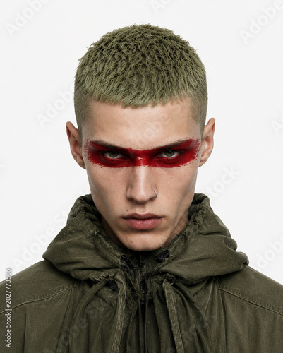 portrait of a young man with red face pain in an olive coat