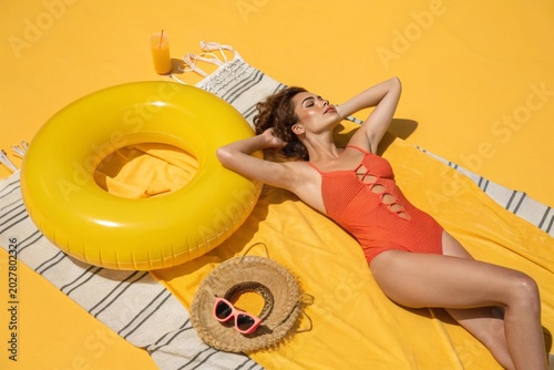 Woman lounges in vibrant orange swimsuit