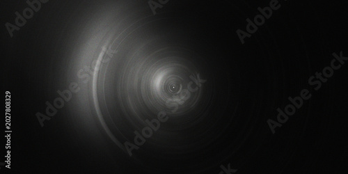 Fotografie Black and white monochrome radial gradient with grainy texture featuring circular motion blur and bright center focal point for art