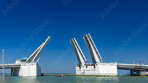 Bild auf Leinwand Wide panoramic view of an open double-leaf bascule drawbridge spanning over a co