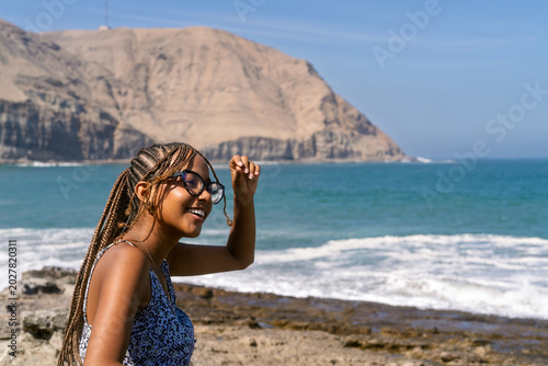Schilderij op canvas Young woman enjoying sunny day at rocky beach