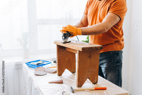Foto Closeup man sanding old wooden stool for restoration project