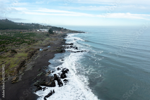 The ocean waves hit the rocky shore. Foam forms as the water moves over the rocks