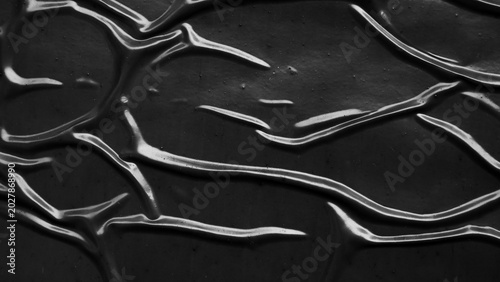 Abstract black wrinkled plastic texture background, dark crumpled surface with light reflections